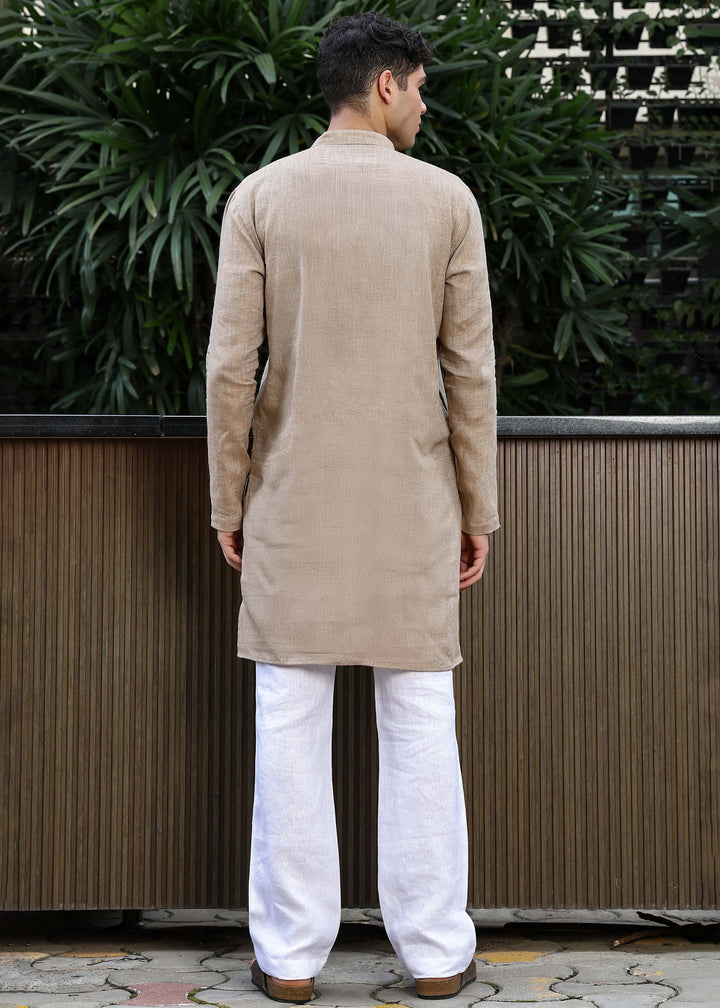 Man wearing a 100% mocha 60 lea Kurta, with placket detail, in a Green outdoor Background.