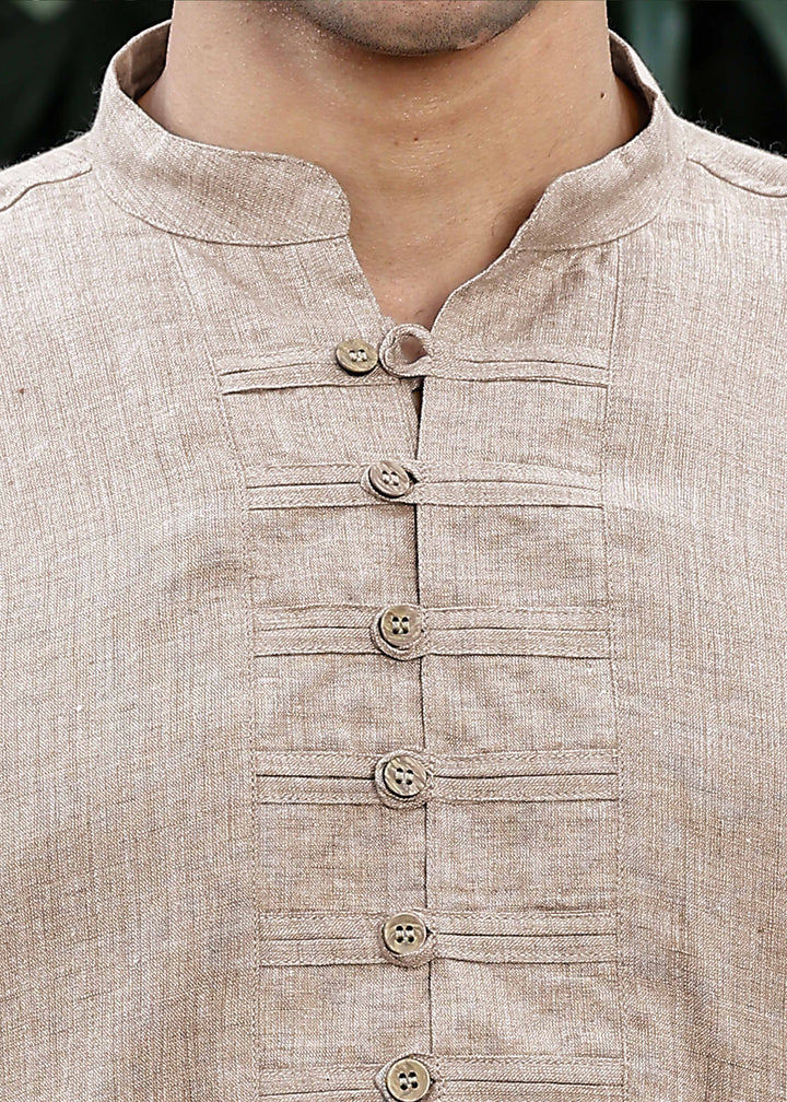 Man wearing a 100% mocha 60 lea Kurta, with placket detail, in a Green outdoor Background.