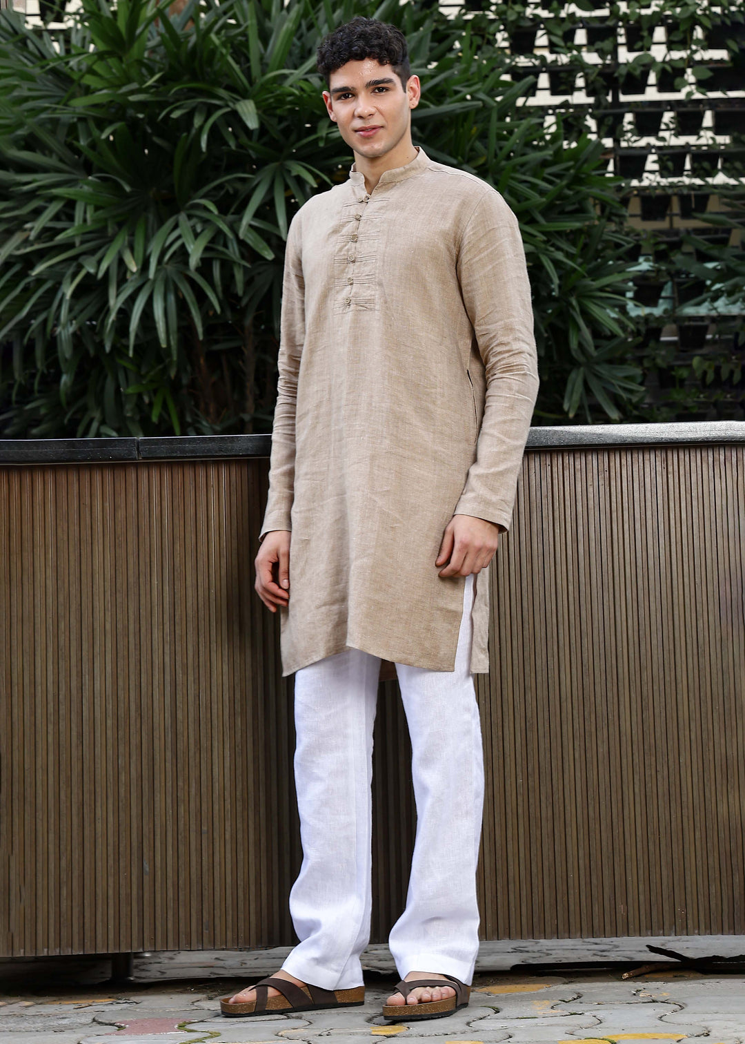 Man wearing a 100% mocha 60 lea Kurta, with placket detail, in a Green outdoor Background.