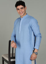 Man wearing a 100% pure linen olympic blue long kurta in 60 LEA with white detailing against a gray background