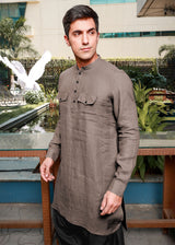 Man wearing a 100% pure linen fawn pink long kurta standing in front of a decorative garden.