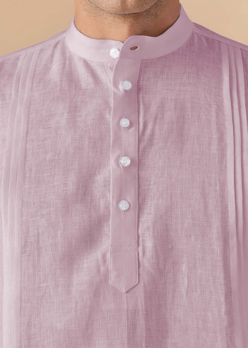 Close-up of a 100% pure linen cameo pink short kurta with white buttons on a beige background