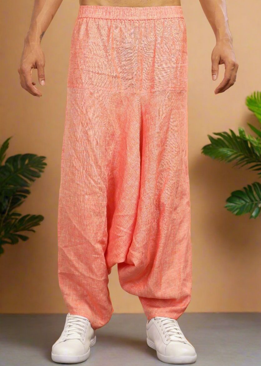 A person standing against a neutral background wearing dark orange chambray linen harem pants with a relaxed fit.