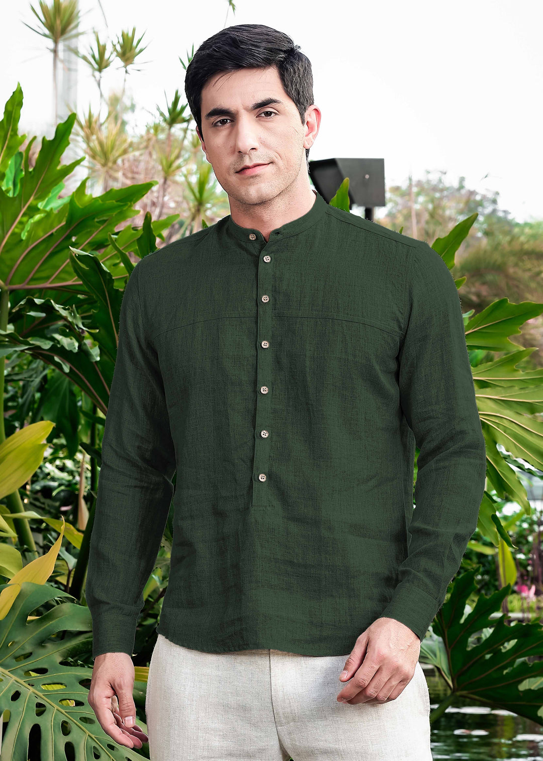 Man wearing a 100% pure linen dark fern green short kurta standing in front of green plants