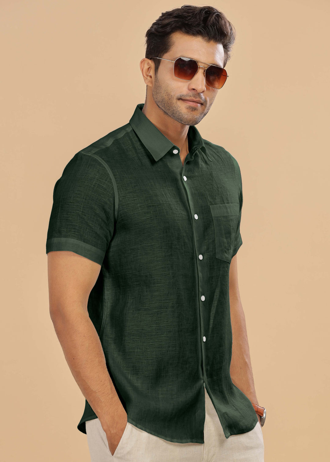 Man wearing a 100% pure linen dark fern green shirt and sunglasses against a beige background