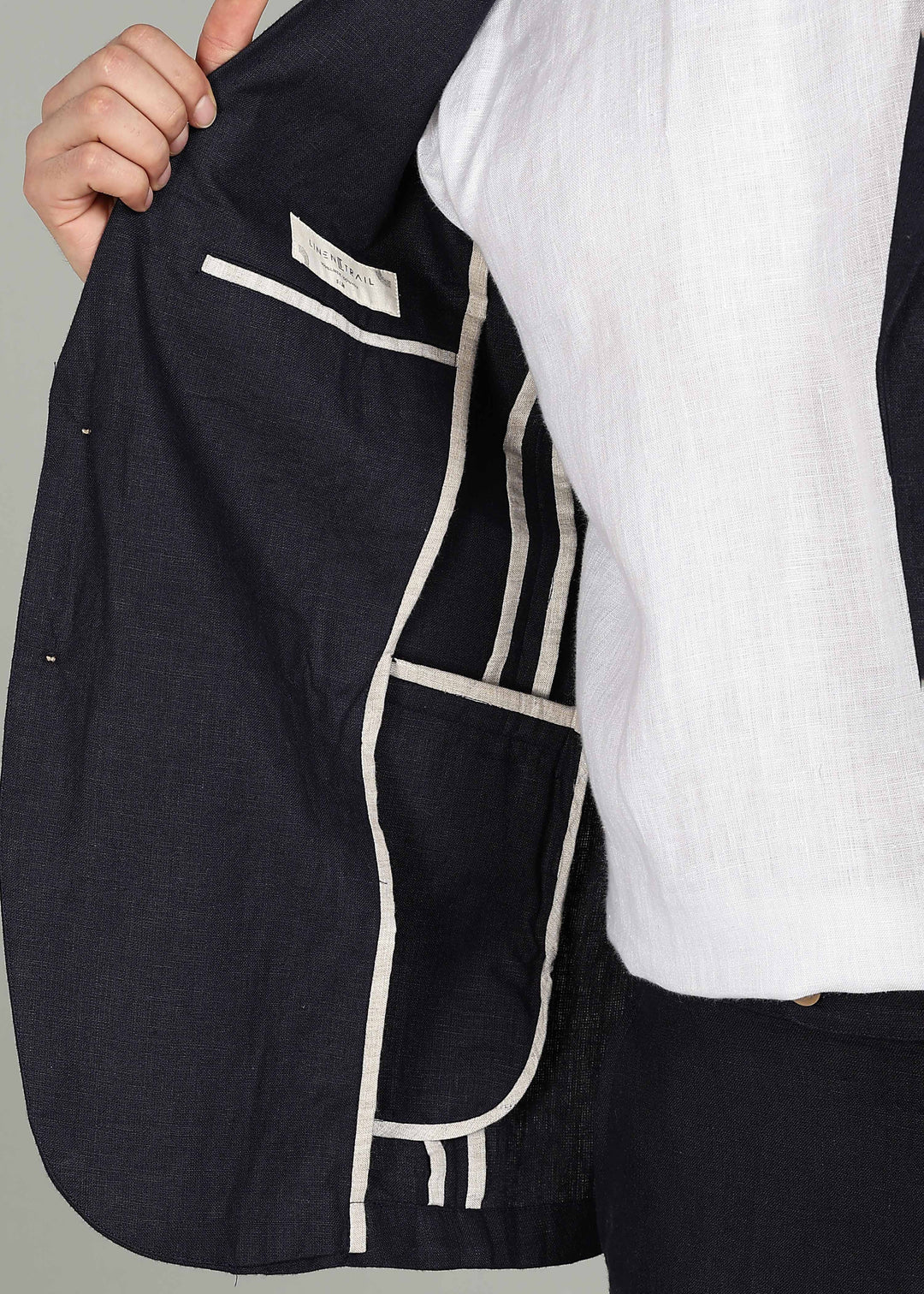 Man wearing a 100% pure linen regal blue jacket in 25 LEA over a white shirt on a gray background
