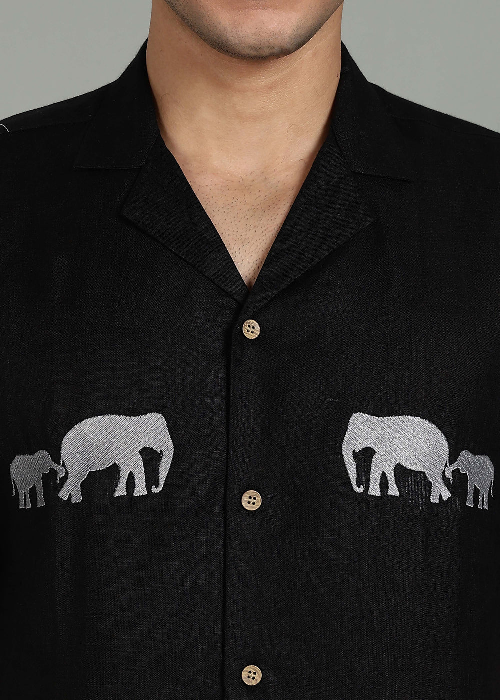 Man wearing a 100% pure linen black shirt in 60 LEA with elephant embroidery on a gray background
