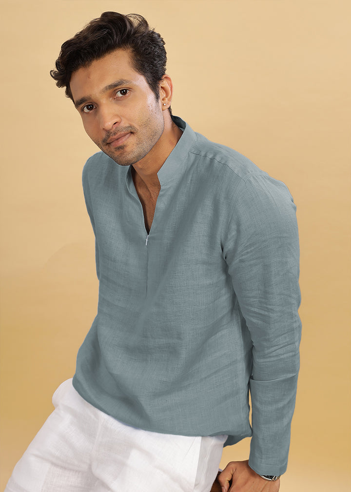 Man wearing a 100% pure linen mineral grey short kurta with white pants against a beige background