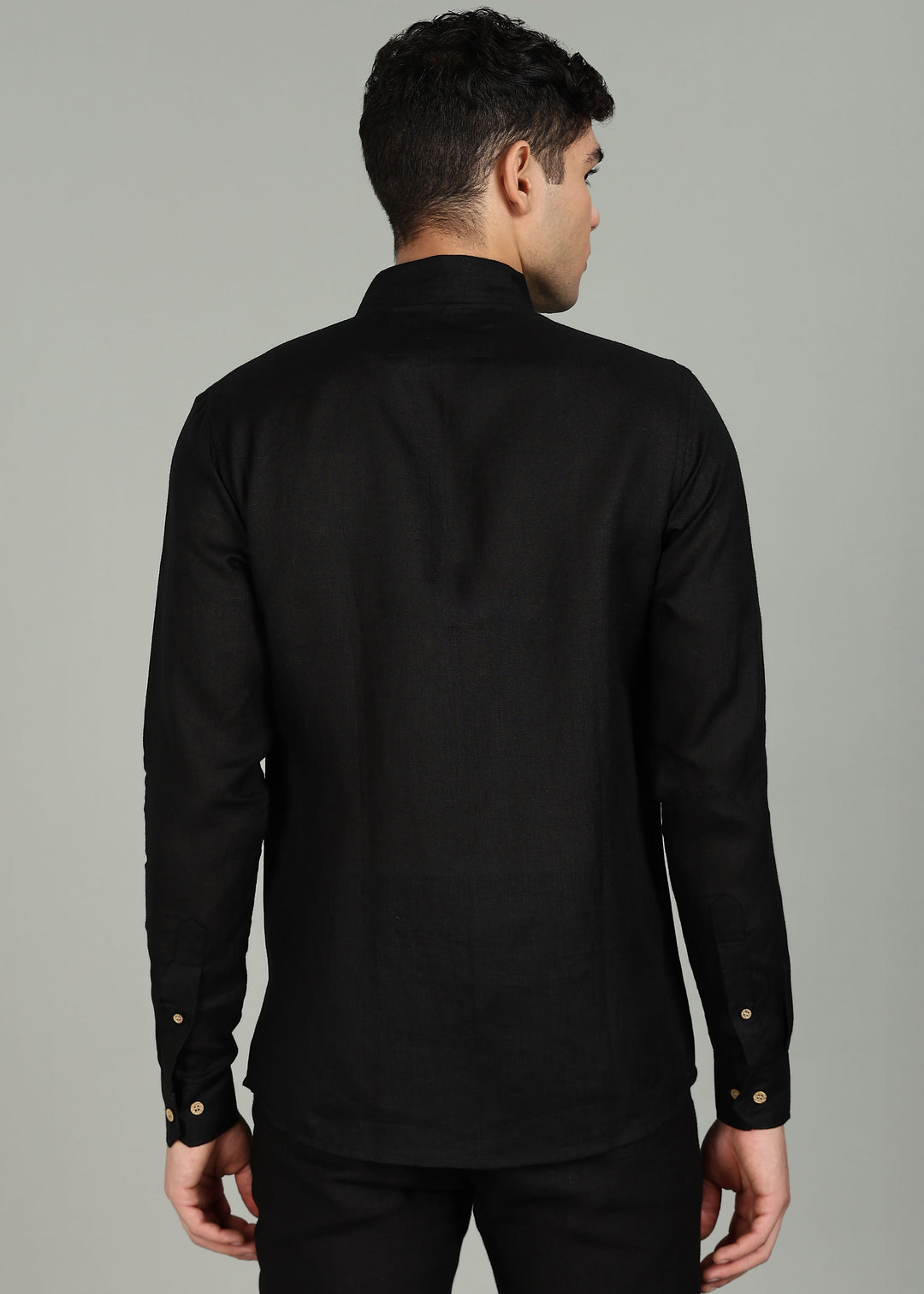 Man wearing a 100% pure linen black shirt in 60 LEA with elephant embroidery against a gray background