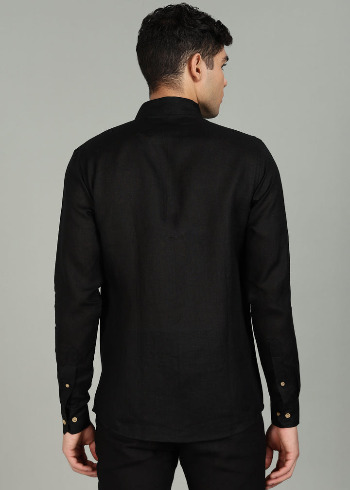 Man wearing a 100% pure linen black shirt in 60 LEA with elephant embroidery against a gray background