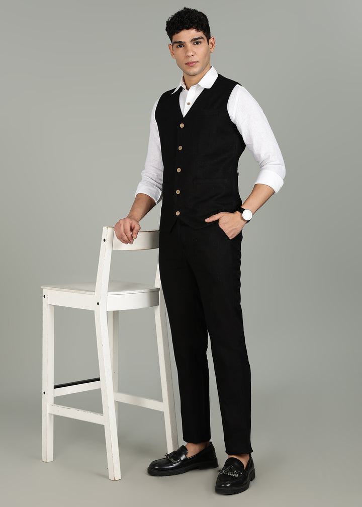 Man wearing a 100% pure linen black waistcoat in 25 LEA over a white shirt against a gray background