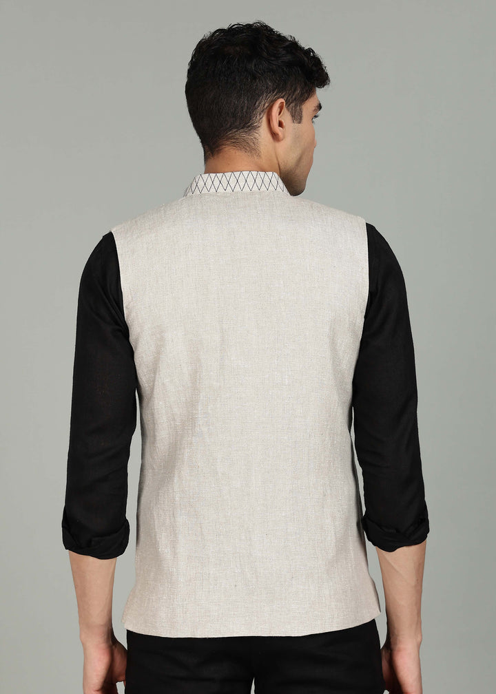 Man wearing an ecru 100% pure linen embroidered vest in 25 LEA over a black shirt on a gray background
