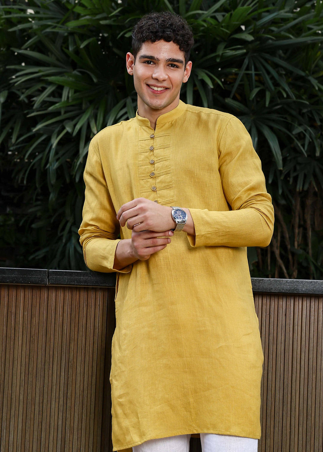 Man wearing a 100% Sunburst yellow 60 lea Kurta, with placket detail, in a Green outdoor Background.