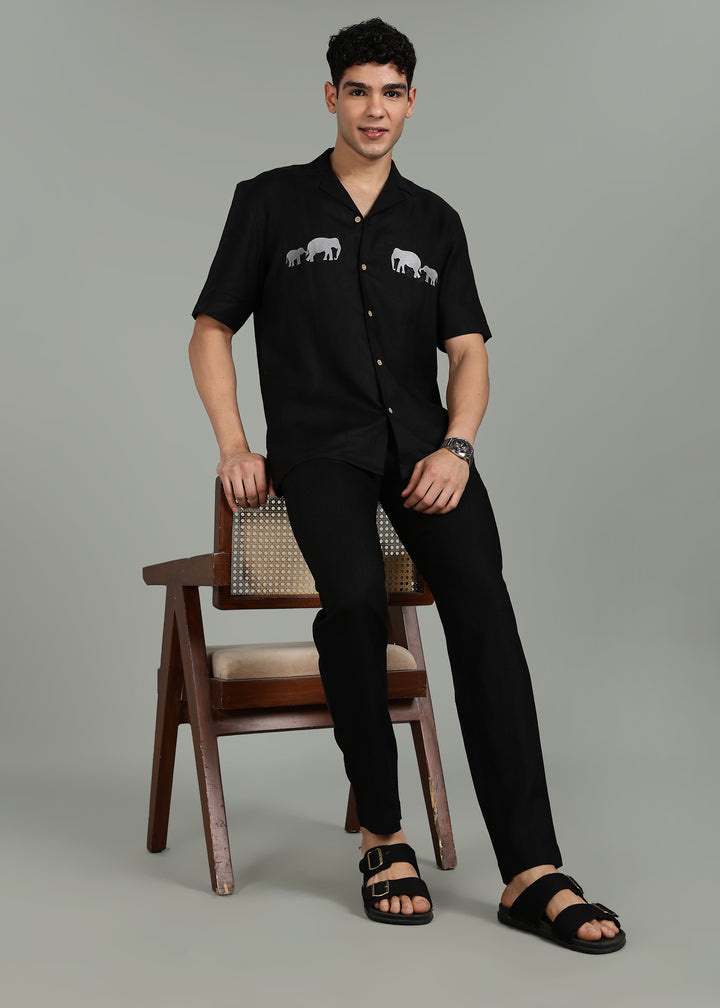 Man wearing a 100% pure linen black shirt in 60 LEA with elephant embroidery on a gray background