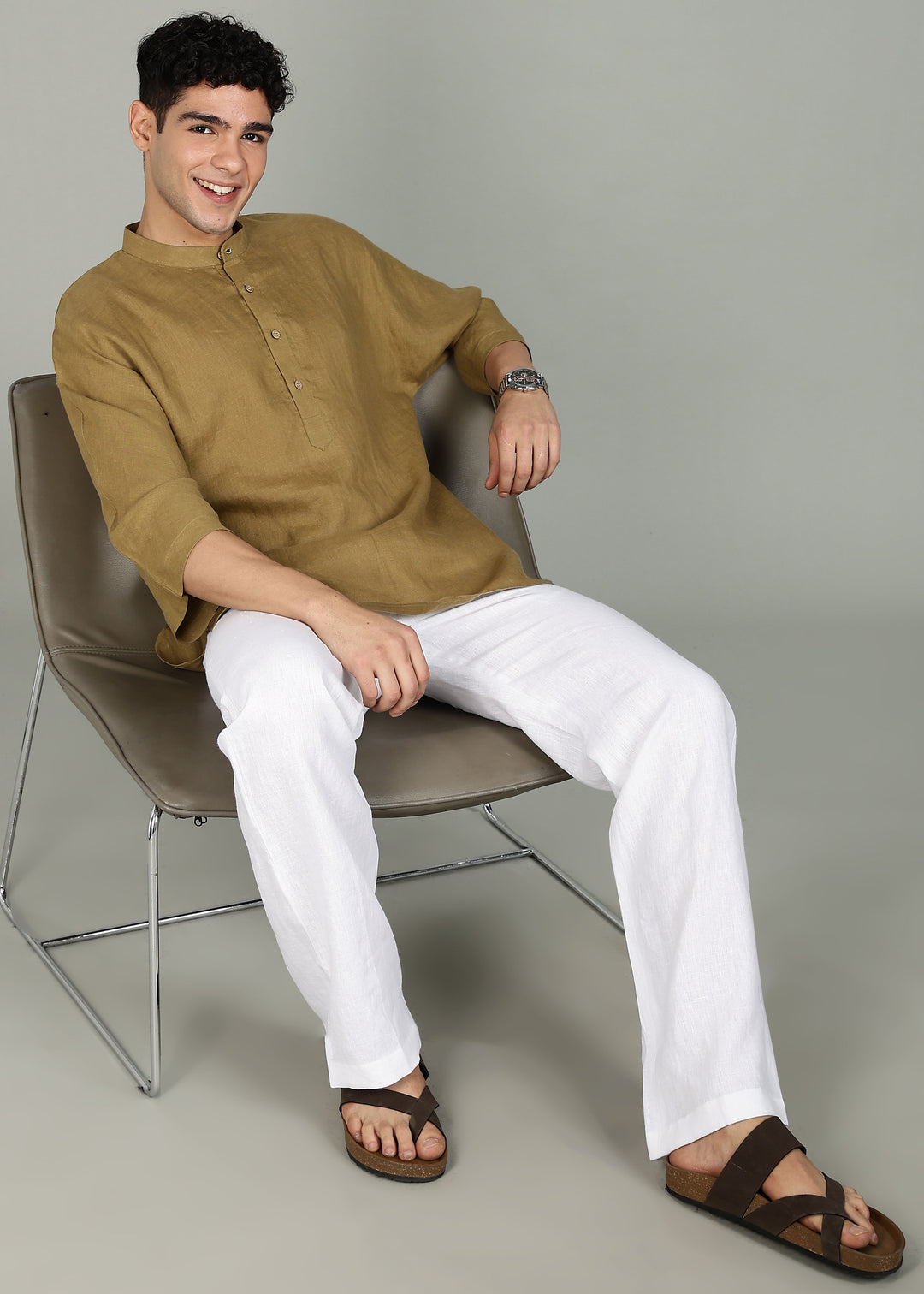 Man wearing a 100% pure linen golden olive green short kurta in 60 LEA with white pants against a gray background
