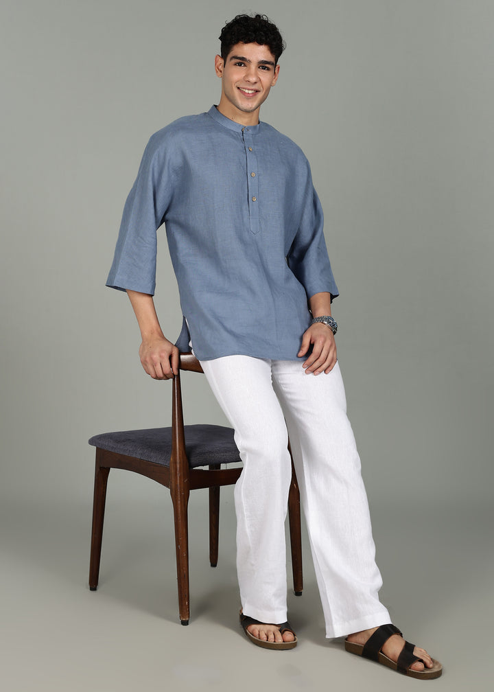 Man wearing a 100% pure linen blue grey short kurta in 60 LEA with white pants against a gray background