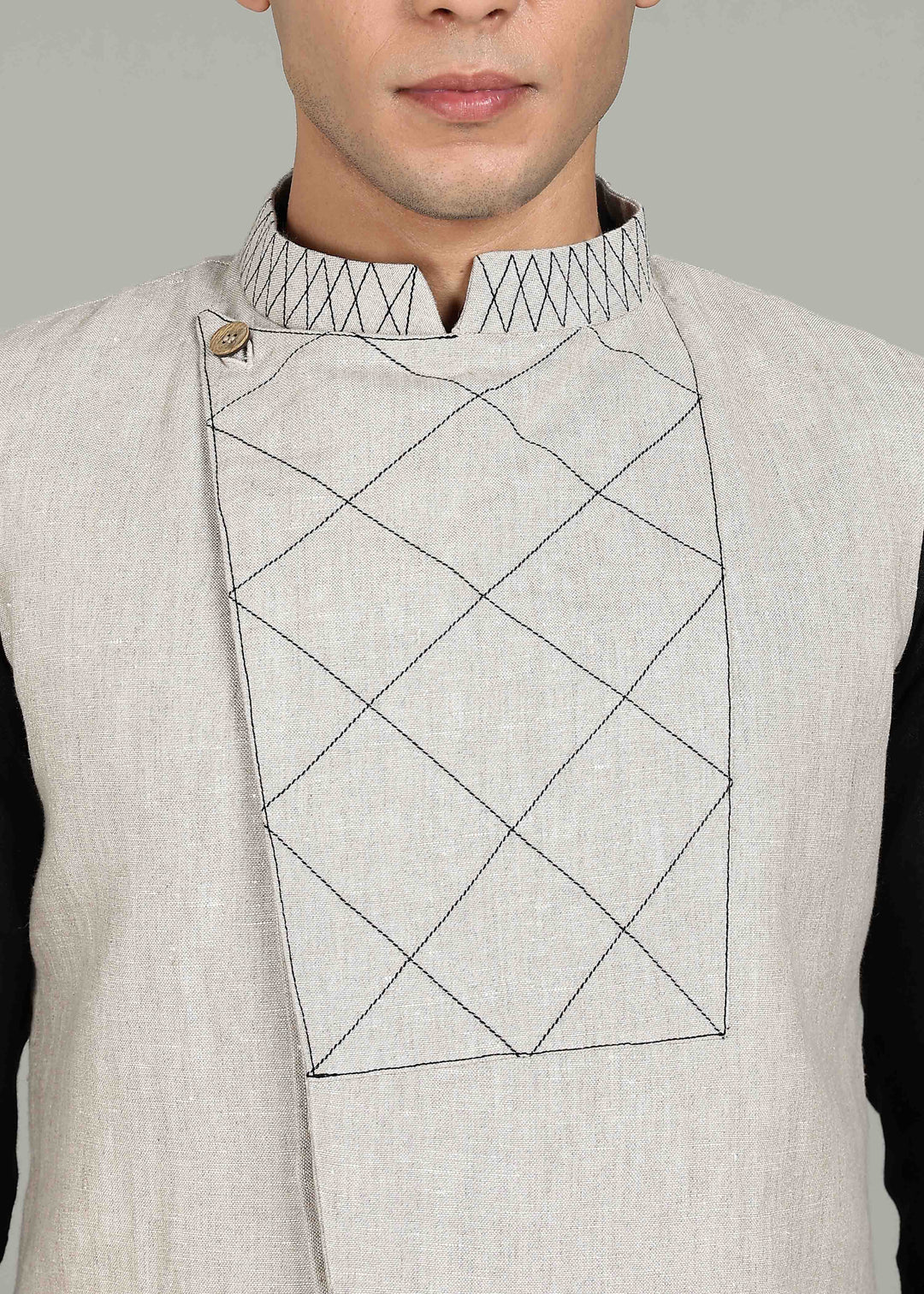 Man wearing an ecru 100% pure linen embroidered vest in 25 LEA over a black shirt on a gray background