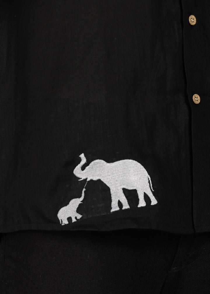 Man wearing a 100% pure linen black shirt in 60 LEA with elephant embroidery against a gray background