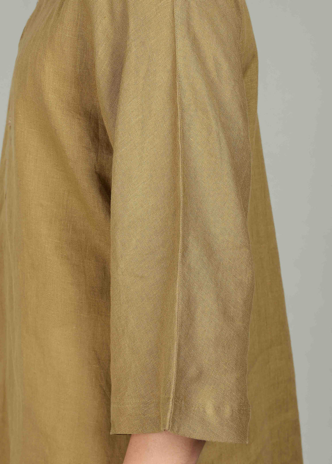 Man wearing a 100% pure linen golden olive green short kurta in 60 LEA with white pants against a gray background