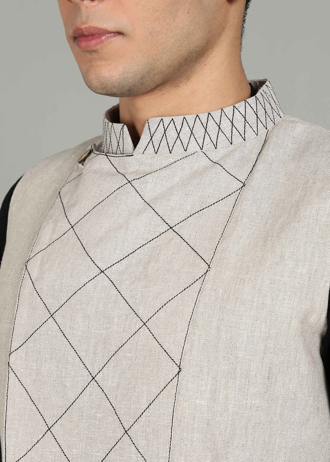 Man wearing an ecru 100% pure linen embroidered vest in 25 LEA over a black shirt on a gray background