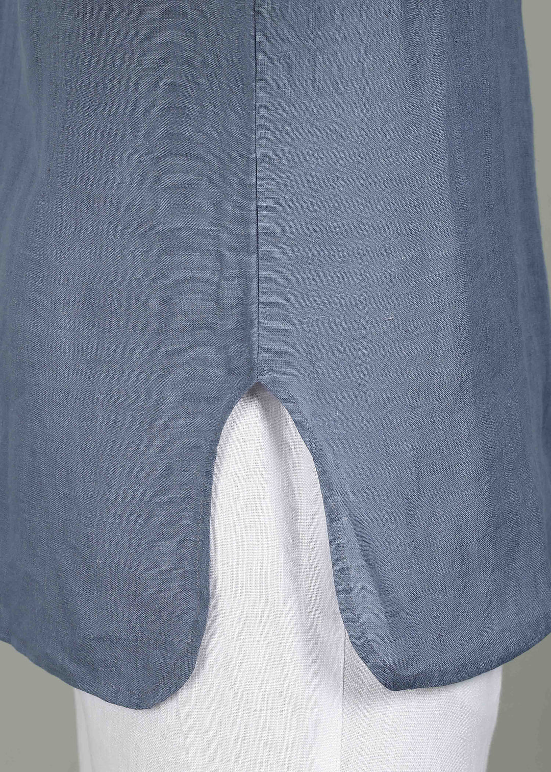 Man wearing a 100% pure linen blue grey short kurta in 60 LEA with white pants against a gray background