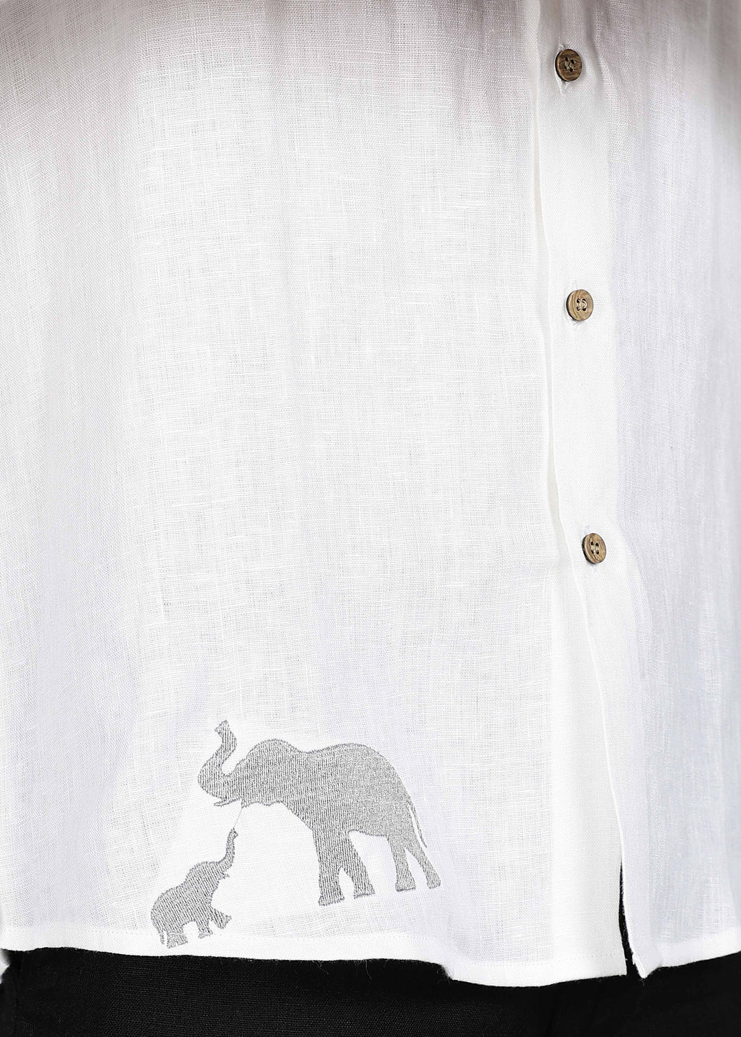 Man wearing a 100% pure linen white shirt in 44 LEA with elephant embroidery sitting on a chair against a gray background