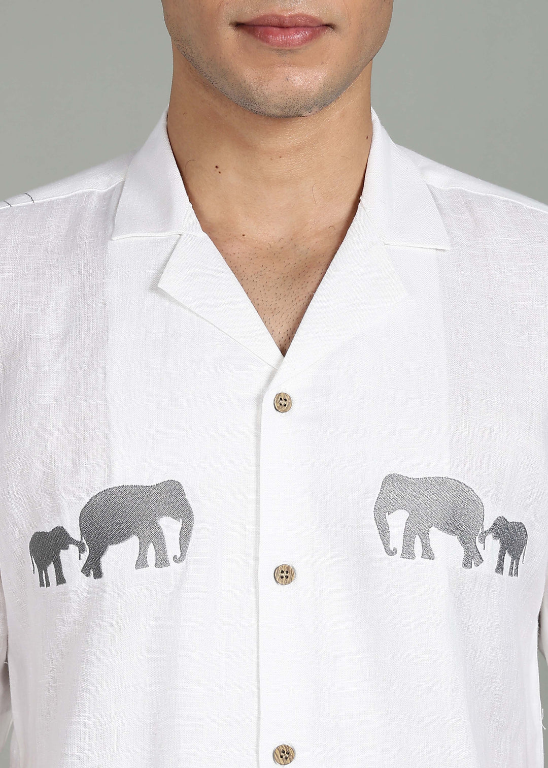Man wearing a 100% pure linen white shirt in 44 LEA with elephant embroidery on a gray background