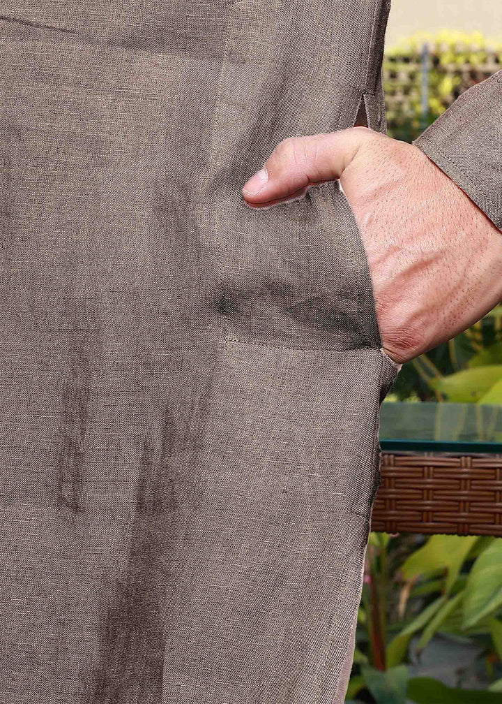 Close-up of a person wearing a 100% pure linen fawn pink long kurta with a pocket, outdoors.