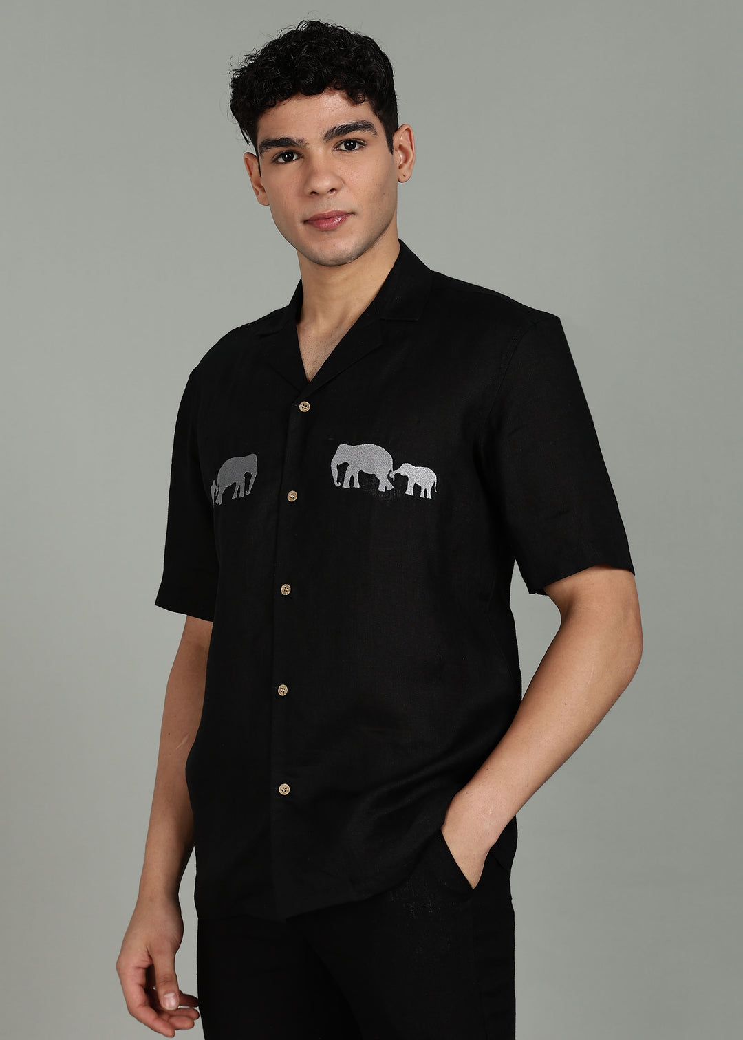 Man wearing a 100% pure linen black shirt in 60 LEA with elephant embroidery on a gray background