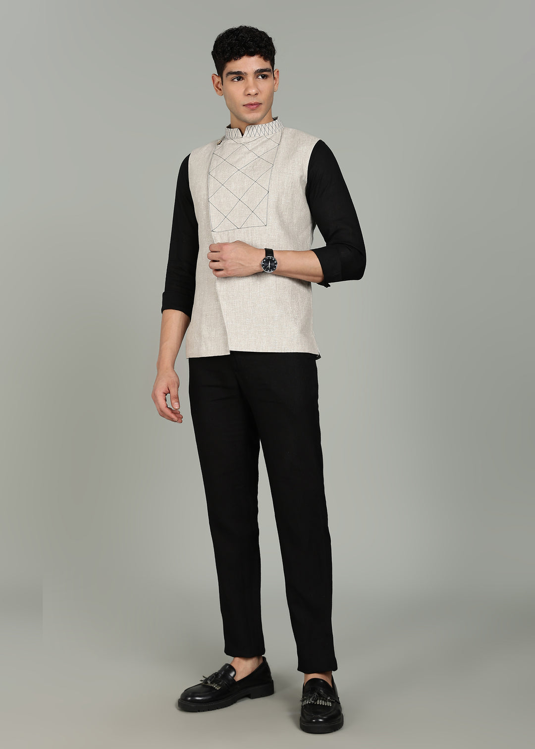 Man wearing an ecru 100% pure linen embroidered vest in 25 LEA over a black shirt on a gray background