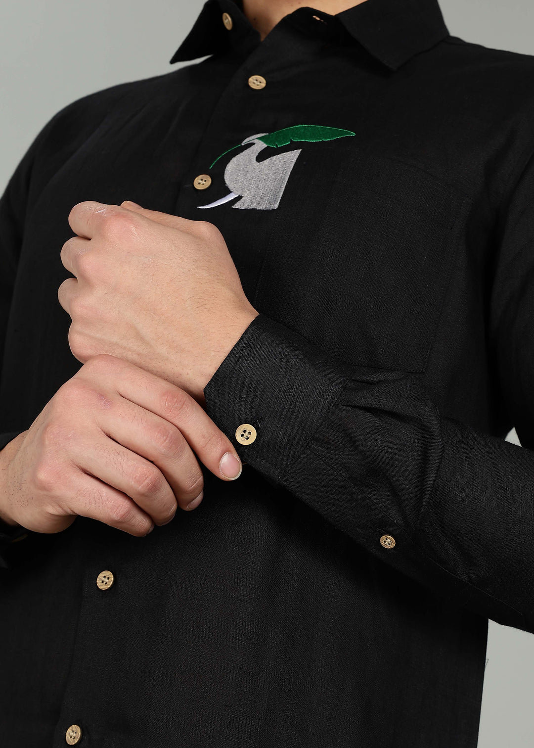 Man wearing a 100% pure linen black shirt in 60 LEA with elephant embroidery against a gray background