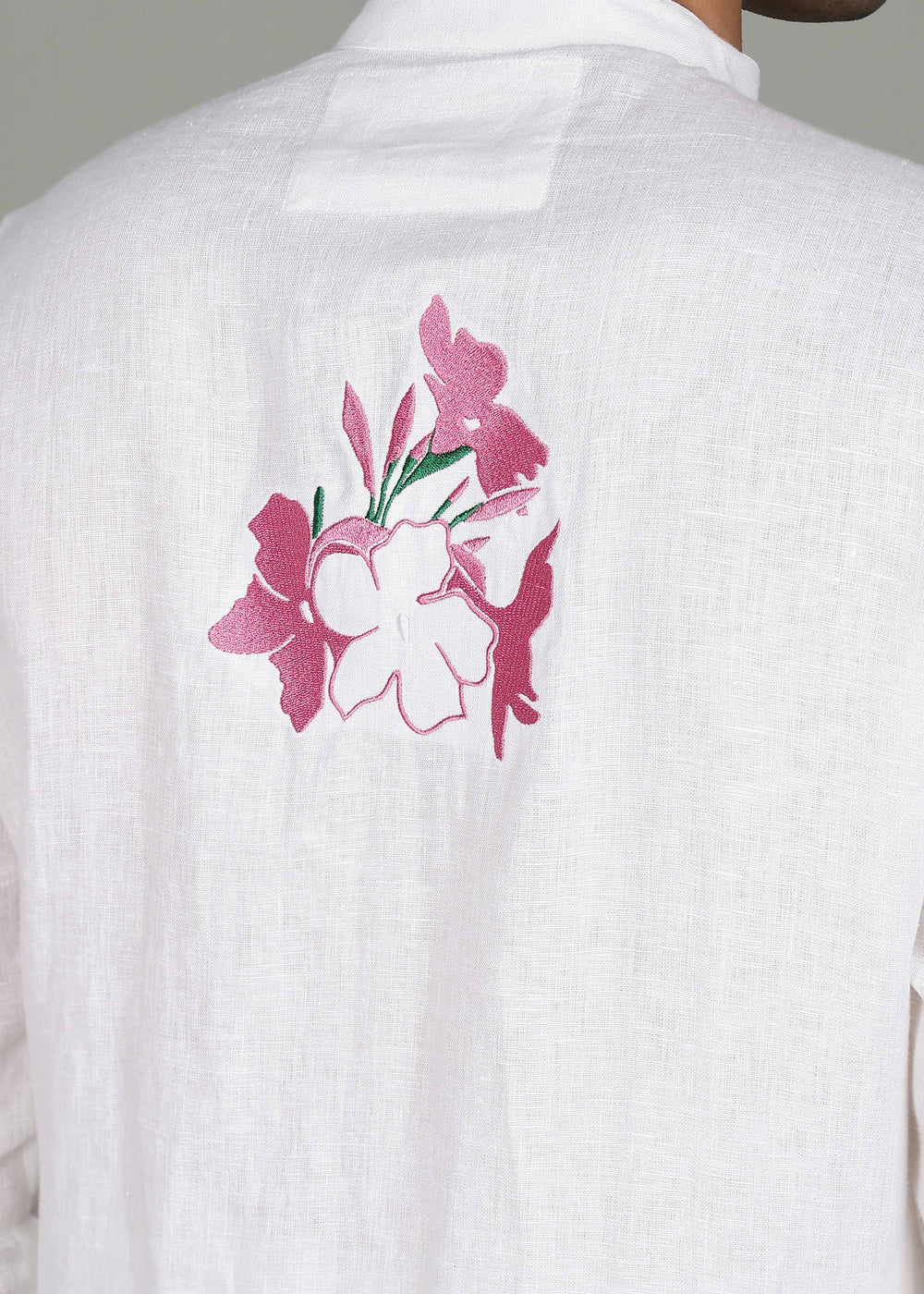 Man wearing a 100% pure linen white long kurta with pink floral design on the back in 44 LEA against a gray background