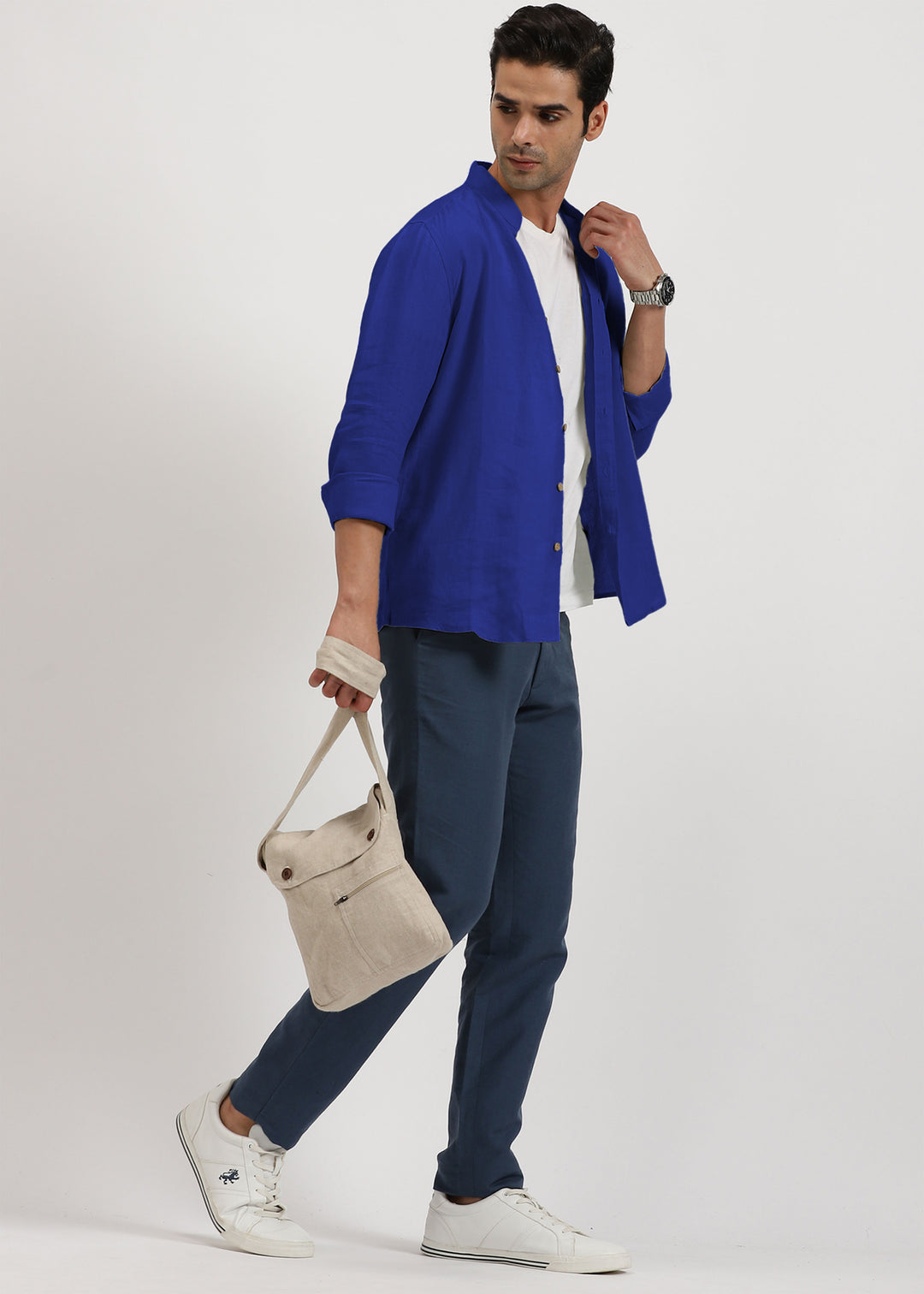Man wearing a 100% pure linen egyptian blue shirt holding a beige bag on a white background