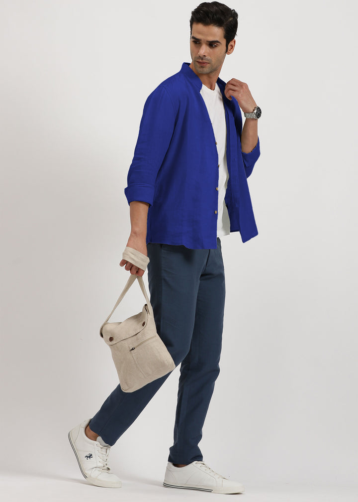 Man wearing a 100% pure linen egyptian blue shirt holding a beige bag on a white background