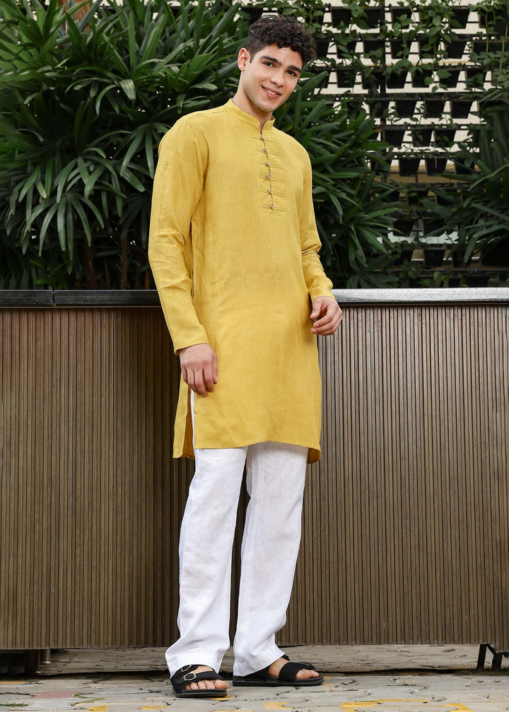 Man wearing a 100% Sunburst yellow 60 lea Kurta, with placket detail, in a Green outdoor Background.