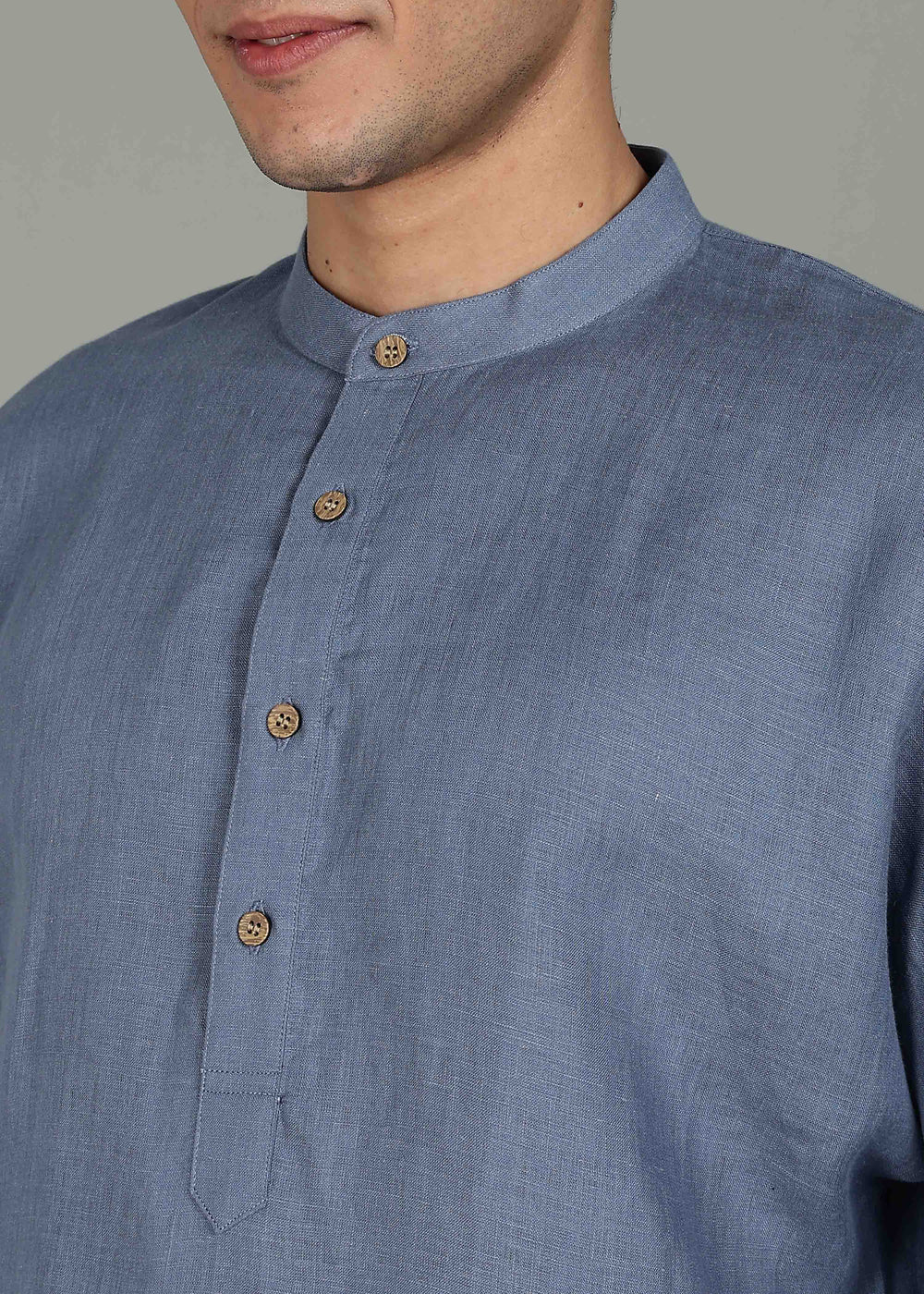 Man wearing a 100% pure linen blue grey short kurta in 60 LEA with white pants against a gray background