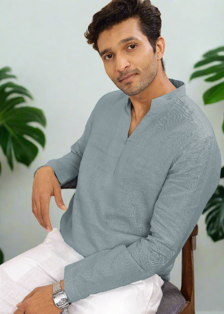 Man wearing a 100% pure linen mineral grey short kurta sitting on a chair with plants in the background