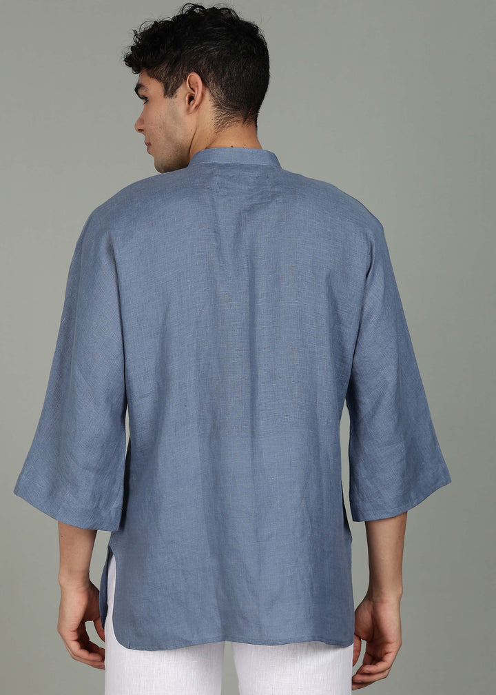 Man wearing a 100% pure linen blue grey short kurta in 60 LEA with white pants against a gray background