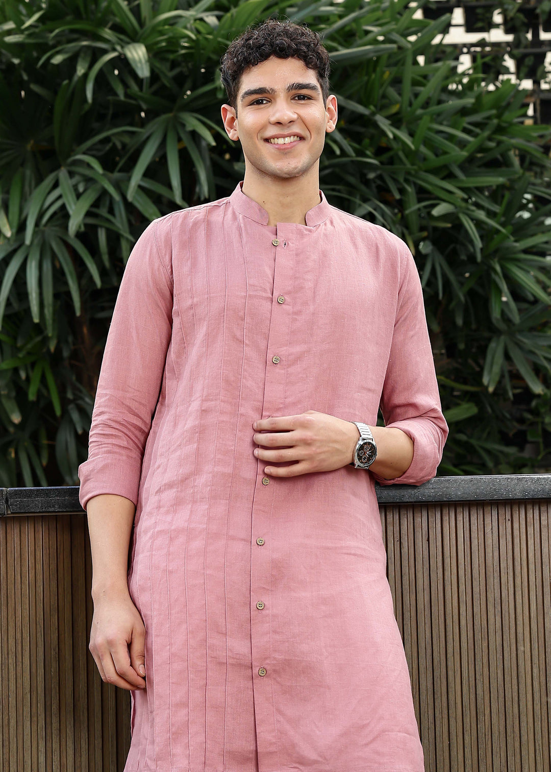 Man wearing a 100% Dusty pink yellow Kurta, in a Green outdoor Background.