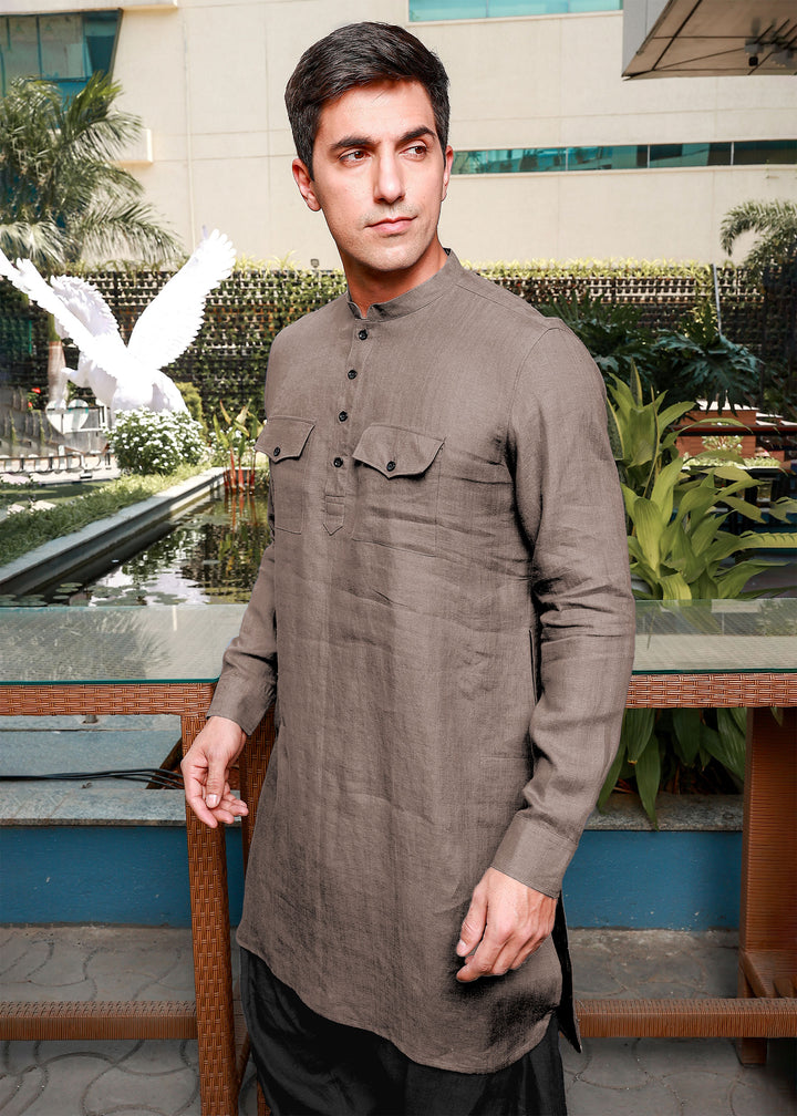 Man wearing a 100% pure linen fawn pink long kurta standing in front of a decorative garden.