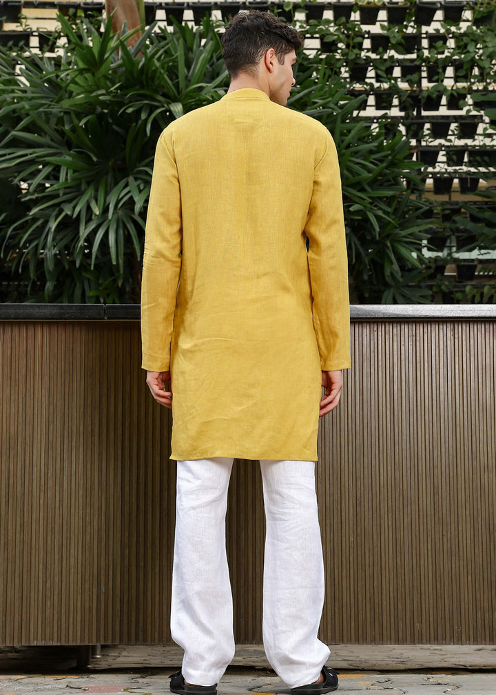 Man wearing a 100% Sunburst yellow 60 lea Kurta, with placket detail, in a Green outdoor Background.