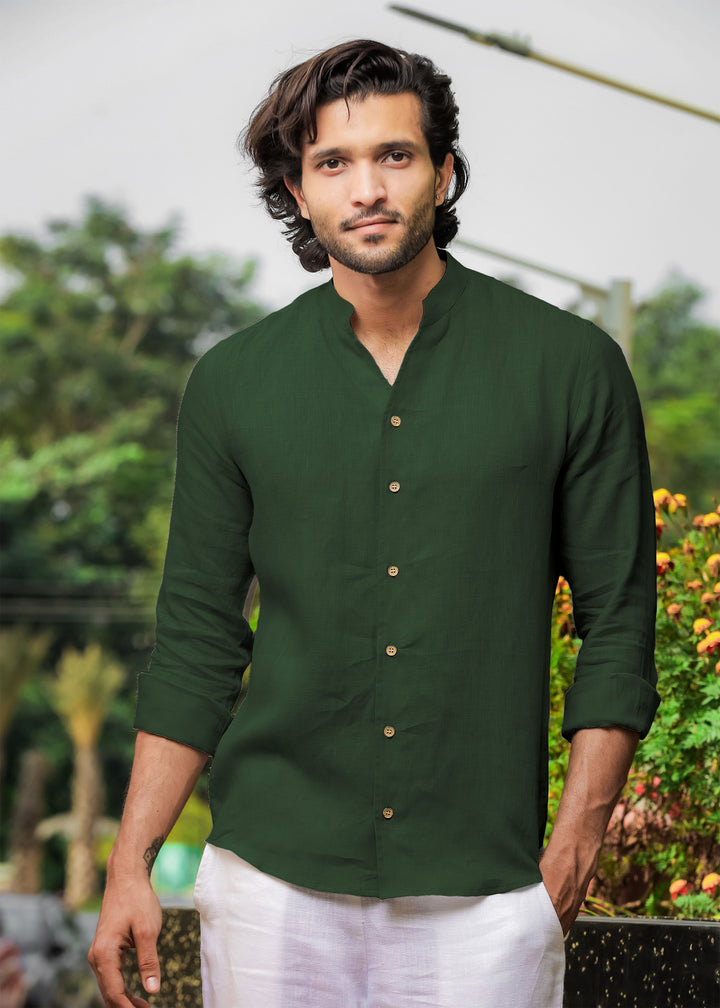 Man wearing a 100% pure linen dark fern green shirt with a blurred natural background