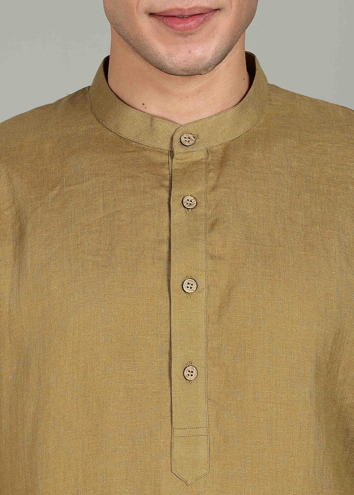 Man wearing a 100% pure linen golden olive green short kurta in 60 LEA with white pants against a gray background