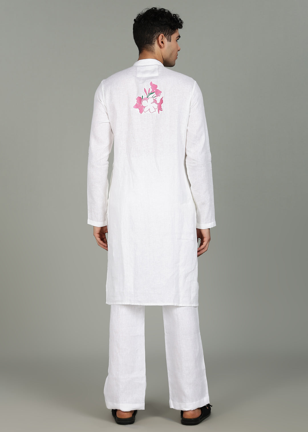Man wearing a 100% pure linen white long kurta with pink floral design on the back in 44 LEA against a gray background