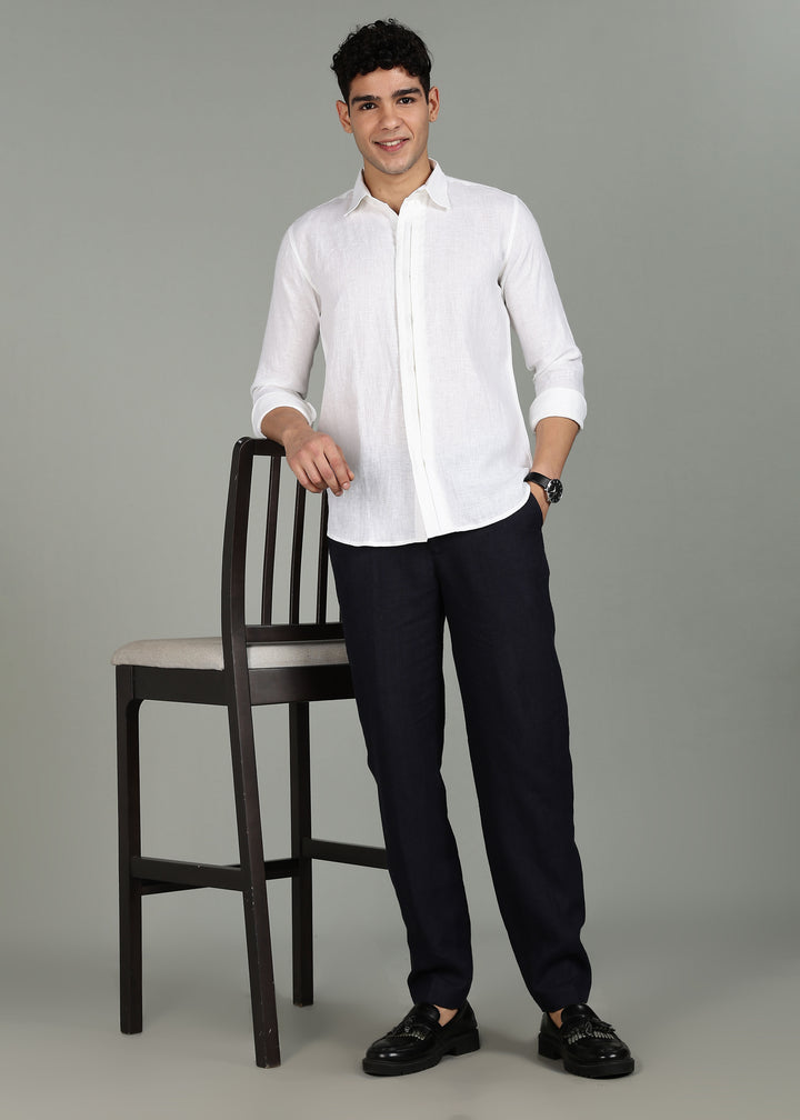 Man wearing a 100% pure linen white full sleeve shirt in 44 LEA  and black pants standing next to a chair on a gray background
