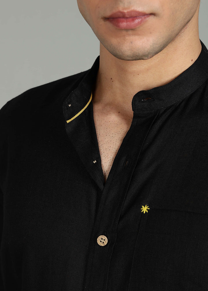 Close-up of a 100% pure linen black full sleeve shirt in 60 LEA with a yellow star emblem on a gray background
