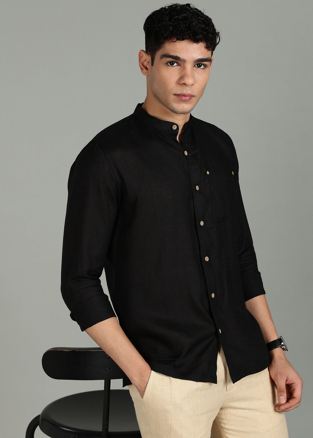 Man wearing a 100% pure linen black full sleeve shirt in 60 LEA with beige pants against a gray background