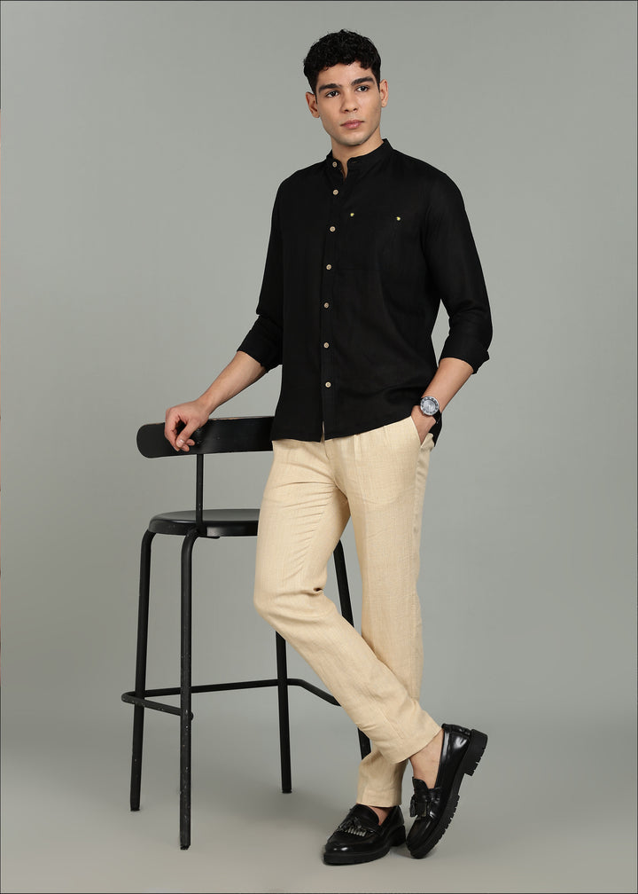 Man wearing a 100% pure linen black full sleeve shirt in 60 LEA, beige pants, and black shoes on a gray background