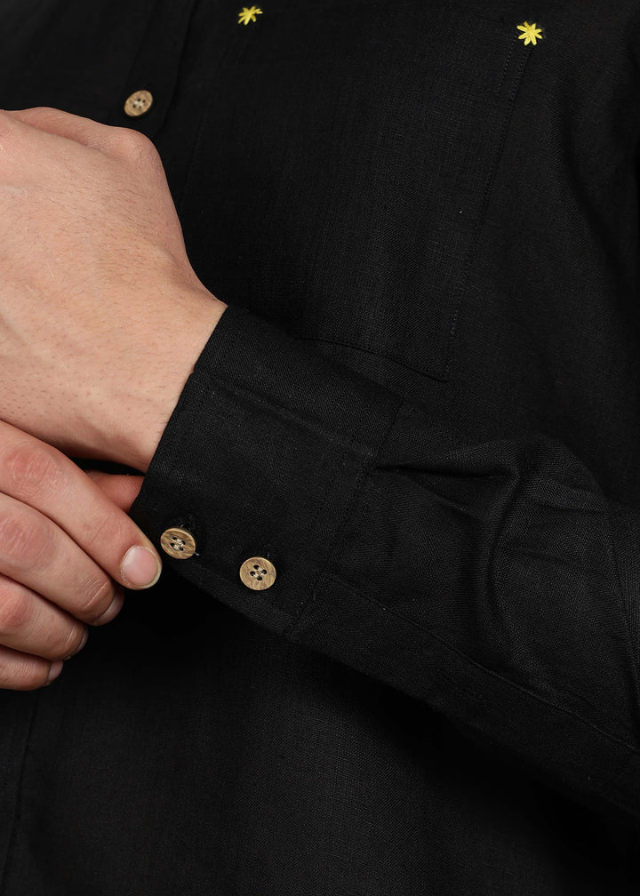 Close-up of a 100% pure linen black full sleeve shirt in 60 LEA with wooden buttons and yellow stars on a dark background