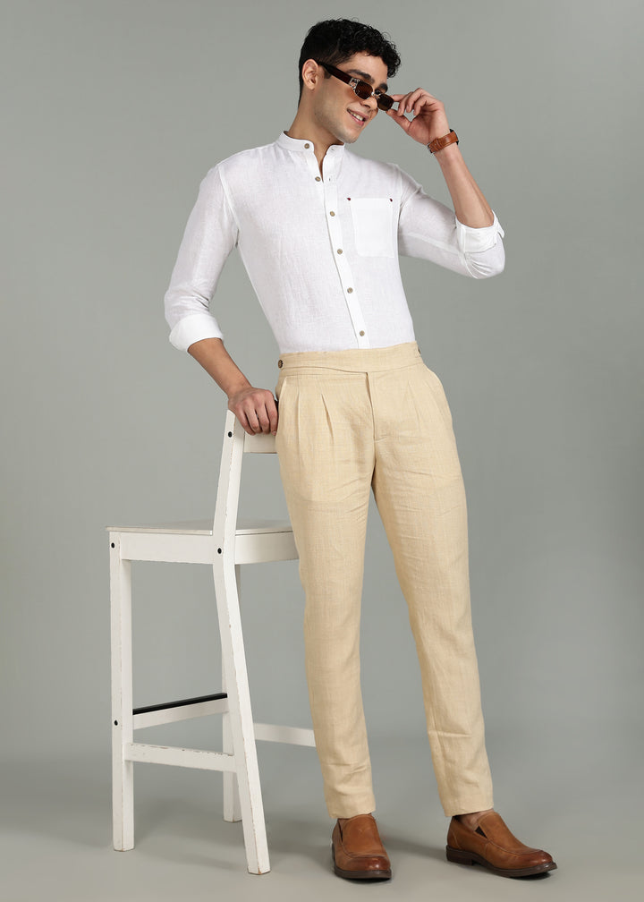Man wearing a 100% pure linen white full sleeve shirt in 44 LEA and beige pants standing next to a white stool on a gray background
